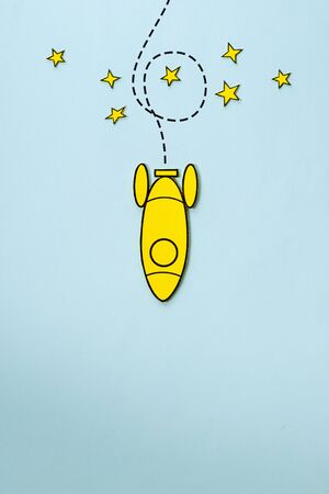 Little yellow rocket looping around stars on its way back to earth over a blue background with copy spaceの写真素材