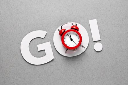 The word go with an alarm clock in a countdown concept with copy space.