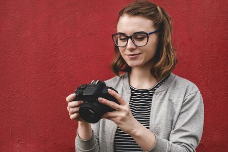Young female photographer checking her image over a red background