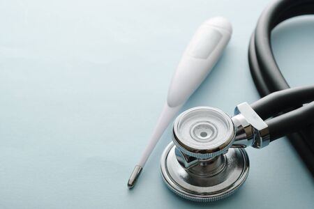 Covid-19 concept with stethoscope and thermometer on a white studio background with copy space for diagnosing or monitoring the respiratory symptoms or feverの写真素材