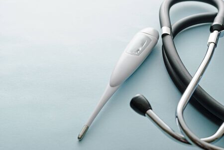 Covid-19 concept with stethoscope and thermometer on a white studio background with copy space for diagnosing or monitoring the respiratory symptoms or feverの写真素材