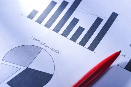Red pen lying on bar and pie business graphs or charts in an office showing production costs in a conceptual imageの写真素材