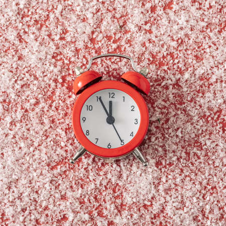 Cute countdown to Christmas with reindeer face formed of snow antlers, cone eyes and a red alarm clock counting down to midnight for a nose over grey with copyspaceの写真素材