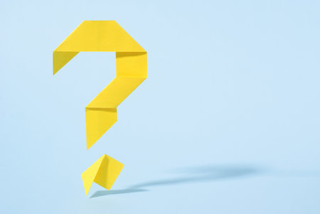 Cut out question mark in a grey card revealing a jumble of colorful party streamers behind in a holiday, carnival or celebration conceptの写真素材