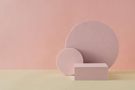 Round and rectangular geometrical shapes on sandy floor, placed against pink wall with copy spaceの写真素材