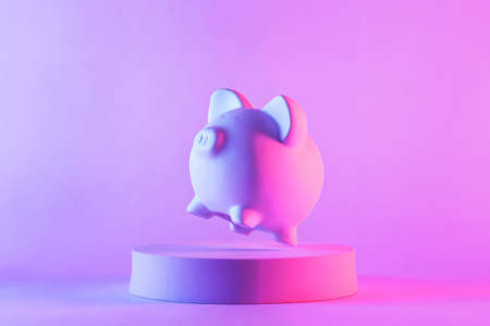Studio close-up of piggy bank floating above a round podium against purple blank background for copy space as symbol for quality saving moneyの写真素材