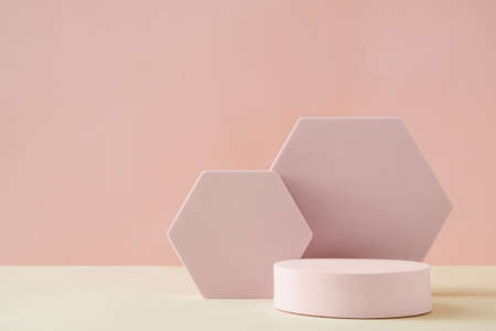 Hexagonal and round 3D shapes, sitting on sandy floor against pink wall in background with copy spaceの写真素材