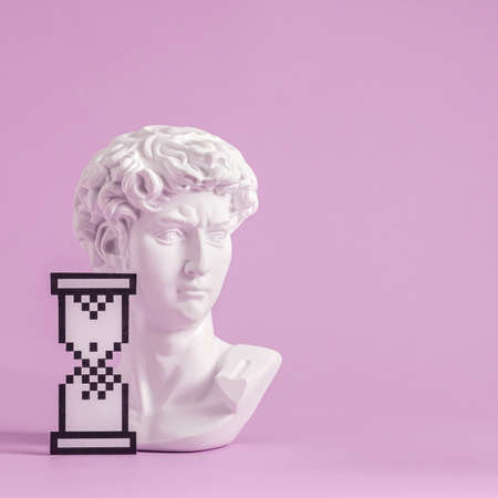 Grecian or Roman bust of a young man with egg timer or hourglass digital symbol over pinkの写真素材