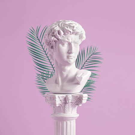 Antique style white Roman or Grecian bust on an ornate pedestal backed with palm fronds over a pink background in square formatの写真素材