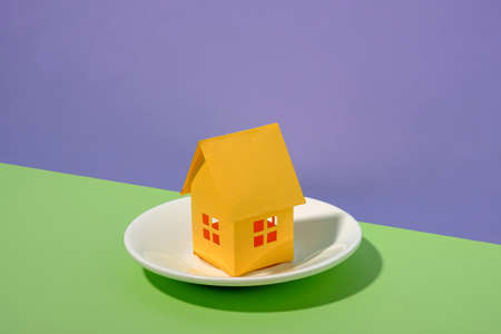 Model house served on a plate over a duo-tone green and blue background with copy space in an eco friendly housing conceptの写真素材