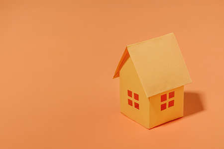 Orange paper house with copy space. The concept of buying a sale and a loan for a house. Minimal concept and pastel color.の写真素材