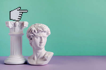 Small white Roman ir Grecian bust on the floor alongside its pedestal over a two tone green and purple background with copy spaceの写真素材