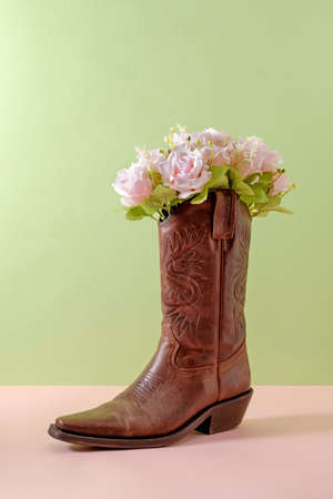 Cowboy boots shoes and bouquet of rose flowers on green background minimal creative concept symbol of wild west america usa texas and party.の写真素材