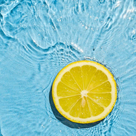 Trend contemporary concept organic juicy fresh lemon in fresh liquid water with splashes. Top view...