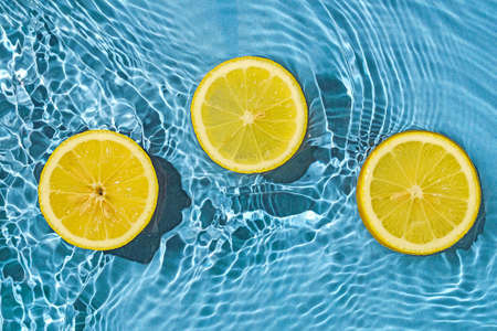 Trend contemporary concept organic juicy fresh lemon in fresh liquid water with splashes. Top view and idea of summer and health.の写真素材