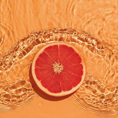 Grapefruit citrus fruit in fresh water with waves on bright background. The concept of summer freshness and healthy nutrition with vitamins.の写真素材