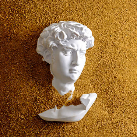 Gypsum David head in dune or sand. Creative concept excavation story and texture effect.の写真素材