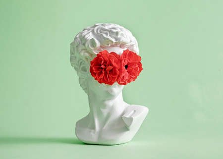 Michelangelo's David head sculpture with rose flower closed eyes and face. Minimal pastel creative vision and look concept.の写真素材