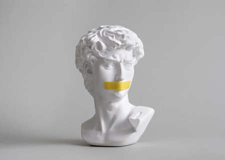 Michelangelo's David head bust in duct tape sealed mouth. Minimal concept on gray background censorship of freedom of speech and restrictions of thought and word. Fight for your rights.の写真素材