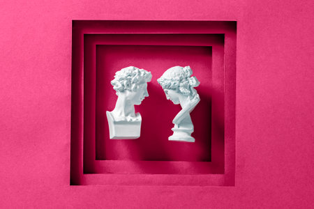 Two antique statues as a young romantic couple framed with a magenta background as a minimal concept of love, happiness and wedding. High quality photoの写真素材