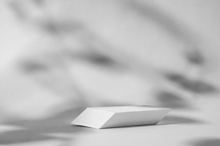 The background of the podium is geometric for advertising a product or cosmetics with shadows from the plant on a white background. High quality photoの写真素材
