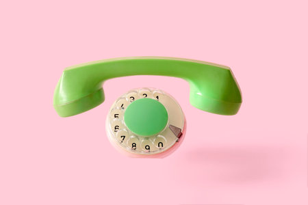 The handset and disc of an old retro phone on a pink background with the absence of the device itself. The concept of a minimal disappeared object. High quality photoの写真素材