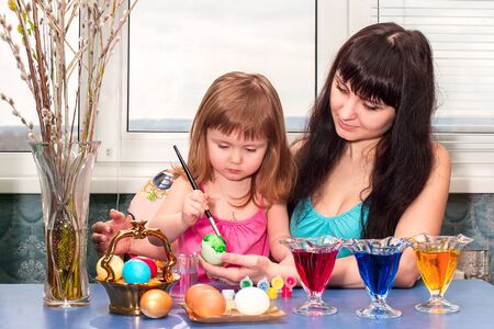 Little girl with mom paints Easter eggs before the holiday.の写真素材
