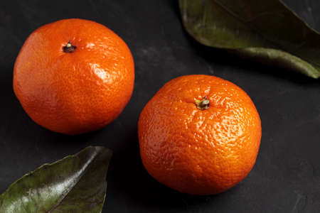 Mandarin, black background. Fresh tangerine fruit with green leaf, dark mood. Clementine citrus plant, healthy, natural, organic. Christmas harvest, healthy vegetarian tangerines closeupの写真素材