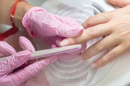 Close-up of girl's fingers and nails during manicure procedure. Nail sawing with nail fileの写真素材