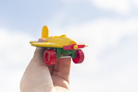 Yellow airplane model with screw closeup in hand on a background of bright sky. Blur background, copy space.の写真素材