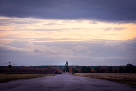 landscape gloomy sky with clouds before the storm and the old highway with potholes on the...