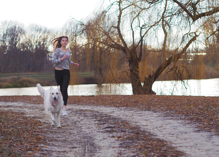 Young girl with dog running at the forest