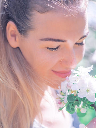 Portrait of young girl at the white spring flowers blossomの写真素材