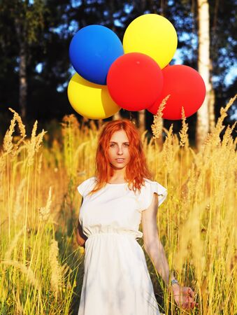 Girl redhead standing with ballons at the yellow spikeletsの写真素材