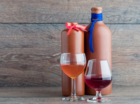 Male and female balm two glasses on a background of clay bottles of balm marked tie and a butterfly on the background of wood.の写真素材