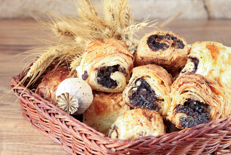 Sweet rolls with poppy seeds lie in a wicker basketの写真素材