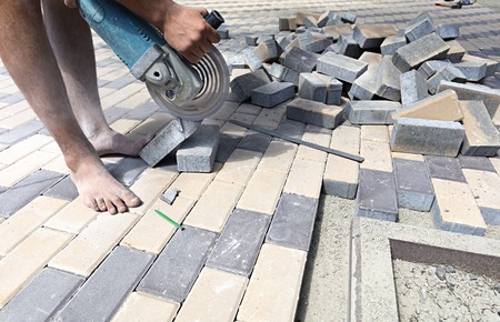 The worker cuts a bar of paving slabs for the final laying on the terraceの写真素材