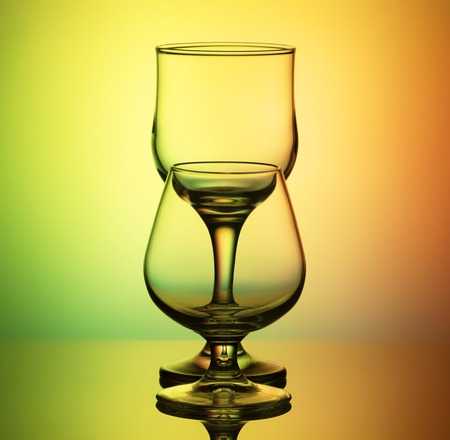 glasses for wine and cognac with a thin contour stand arches after the other, on a bright yellow-green backgroundの写真素材