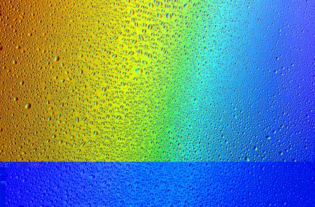 Drops of water against the background of the rainbow and with its reflection in themの写真素材