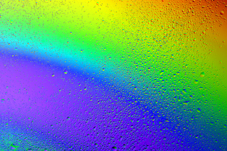 Drops of water against the background of the rainbow and with its reflection in themの写真素材