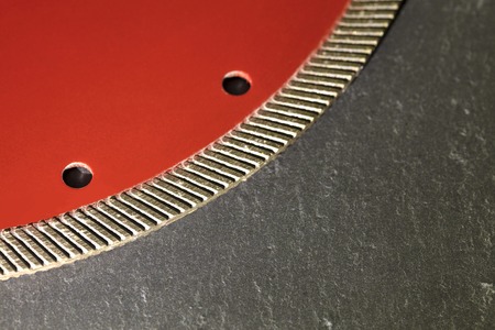 Segment of a diamond red disc for cutting against a gray granite background close-up.の写真素材
