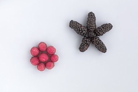 Ripe berries of raspberries and big black blackberry are located diagonally on a light background, the image in a high keyの写真素材