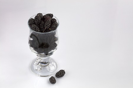 Ripe mulberry are arranged in a clear glass on a light background, a picture in a high keyの写真素材