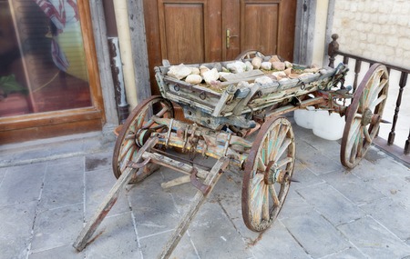 On an old wooden cart there is a pile of clay pots on the background of the entrance doors of the old houseの写真素材