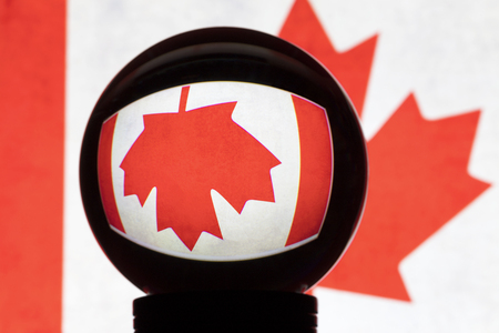 Flag of Canada in reflection on a crystal ball against a blurred canadian flagの写真素材