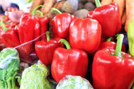Large ripe red sweet bell peppers close-up on the background of other vegetables are sold in trays...
