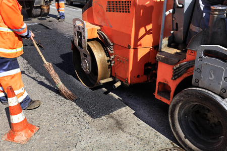 The road roller with the road service team installs asphalt and repairs the road section.の写真素材
