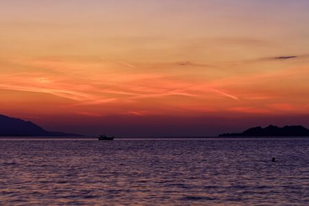 The silhouette of a sea boat that goes along the water surface of the sea against the backdrop of a...