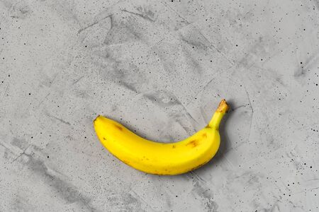 Yellow ripe banana on a gray concrete background, flat lay, image with copy space.の写真素材