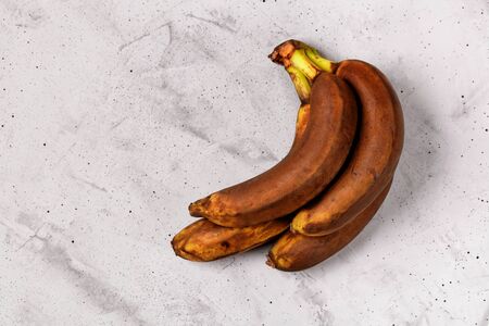 Ugly brown ripe bananas on a gray concrete background, flat lay, image with copy space.の写真素材